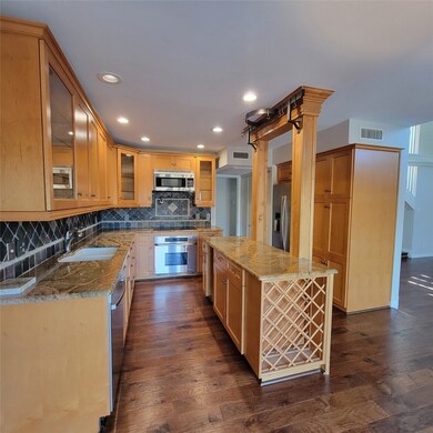 Kitchen featuring backsplash, dark wood-style floors, stainless steel appliances, recessed lighting, and light stone countertops