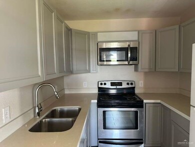 Kitchen featuring gray cabinets, stainless steel appliances, and light stone counters