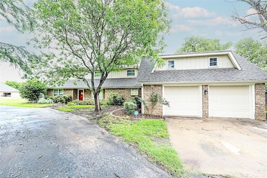 View of front of house featuring driveway, brick siding, and roof with shingles