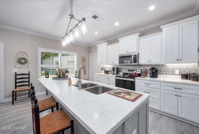 Kitchen with stainless steel appliances, tasteful backsplash, a center island with sink, light wood-type flooring, and a breakfast bar area
