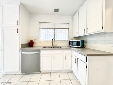Kitchen with white cabinetry, stainless steel appliances, tasteful backsplash, and light tile patterned flooring