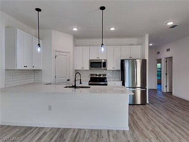 This is a picture of a previously completed home. Kitchen featuring sink, white cabinetry, light wood-type flooring, and stainless steel appliances