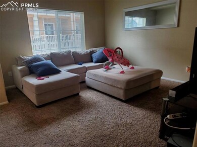 Living area with baseboards, carpet flooring, and a healthy amount of sunlight