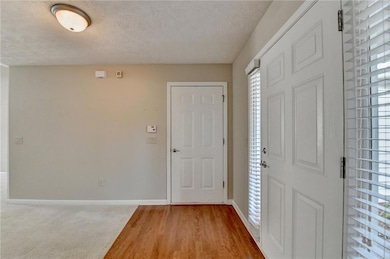 Entrance foyer featuring baseboards, a textured ceiling, and light wood-type flooring