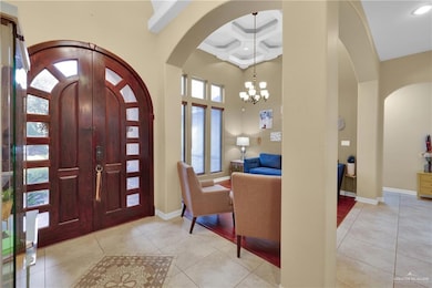 Entrance foyer with arched walkways, coffered ceiling, tile patterned floors, a chandelier, and a towering ceiling
