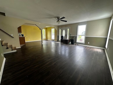 Unfurnished living room with a ceiling fan, baseboards, dark wood-style flooring, arched walkways, and a textured ceiling