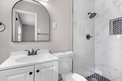 Bathroom featuring vanity, toilet, and tiled showe