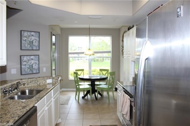 Kitchen with light tile patterned floors, white cabinets, stainless steel appliances, light stone countertops, and sink