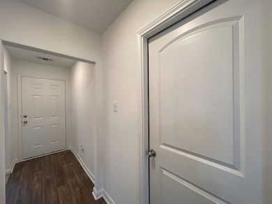 Hallway with dark wood-type flooring and baseboar