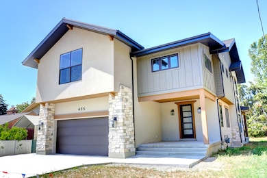 Contemporary house featuring a garage, stone siding, and stucco siding