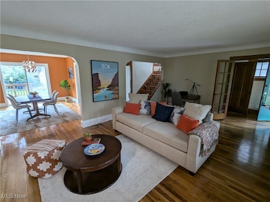 Living room with a textured ceiling, wood-type flooring, and a chandelier