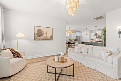 Living room featuring light wood-style flooring, a chandelier, baseboards, and recessed lighting
