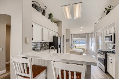Quartz countertops, tiled backsplash, stainless steel appliances and white cabinetry.