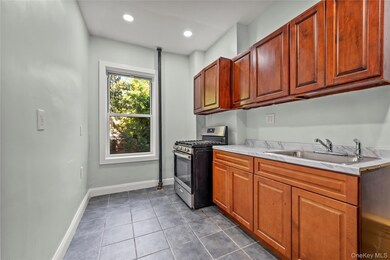 Kitchen with stainless steel gas range, dark tile patterned flooring, brown cabinets, and recessed lighting