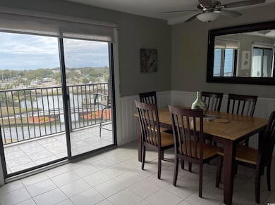 Dining space featuring a water view, a ceiling fan, and wainscoting