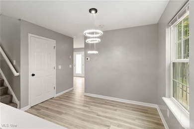 Unfurnished dining area with stairs, light wood-style flooring, and a chandelier