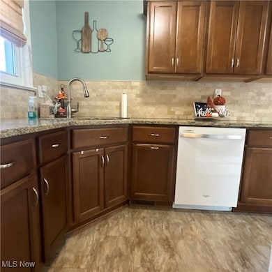 Kitchen featuring light stone countertops, dishwasher, and decorative backsplash