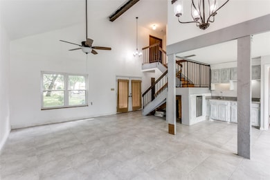 Lving room featuring high vaulted ceiling, beam ceiling, light tile flooring, and ceiling fan with notable chandelier