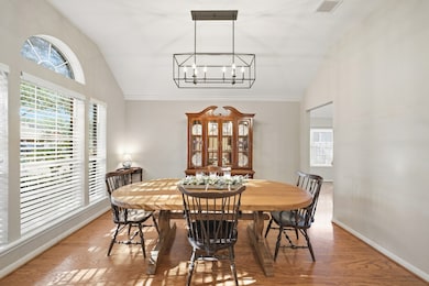 The elegant formal dining room is perfect for hosting. It boasts a modern rectangular chandelier, vaulted ceilings, and large arched windows allowing tons of natural light.