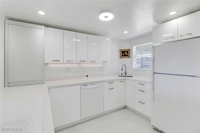 Kitchen featuring white appliances, white cabinetr