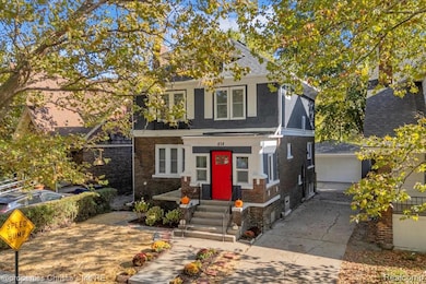 View of front of home with brick siding, a garage, and an outbuilding