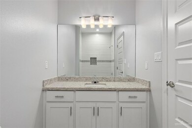 Bathroom featuring a tile shower and vanity
