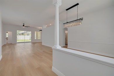 Experience the wow factor of this open-concept great room featuring a show-stopping crystal chandelier and soaring ceilings with elegant columns. The beautiful luxury vinyl plank flooring flows seamlessly throughout, while French doors lead to additional living spaces.