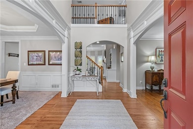 Foyer with light wood-style flooring, arched walkw