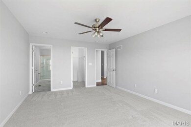 Unfurnished bedroom featuring ceiling fan, light colored carpet, a spacious closet, and a closet
