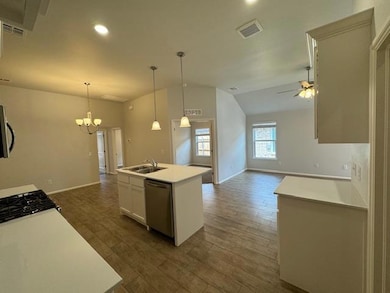 Kitchen with vaulted ceiling, light countertops, open floor plan, pendant lighting, and dark wood-type flooring