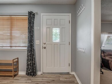 Foyer entrance featuring wood finished floors, healthy amount of natural light, baseboards, and a textured ceiling