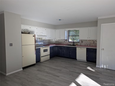 Kitchen featuring white cabinets, white appliances, decorative backsplash, and dark wood-style flooring