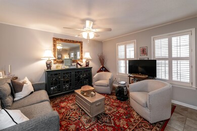 Tiled living room featuring ceiling fan and crown molding