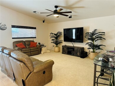 Carpeted living area with ceiling fan and vaulted