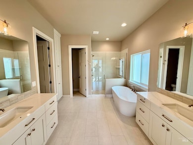 Full bath featuring a freestanding bath, a shower stall, two vanities, recessed lighting, and light tile patterned flooring