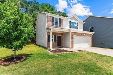 View of front facade featuring brick siding, driveway, an attached garage, and a front lawn
