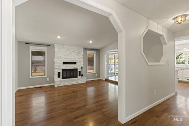 Unfurnished living room with dark wood-style flooring, a stone fireplace, and a textured ceiling