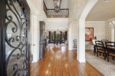 Hardwood & tile floors are featured throughout the entire first level of the home and the foyer includes a two-story ceiling with wrought iron balcony views from the media & game room above. Double arched openings with custom moulding open to the formal dining room on the right.