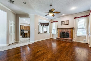Family room with ceiling fan, crown molding, a fireplace, a textured ceiling, and hardwood / wood-style flooring
