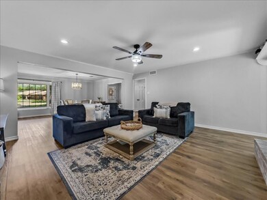 Living room with ceiling fan with notable fan chandelier and LVP flooring