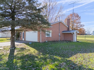 View of home's exterior featuring driveway, brick siding, a yard, and a chimney