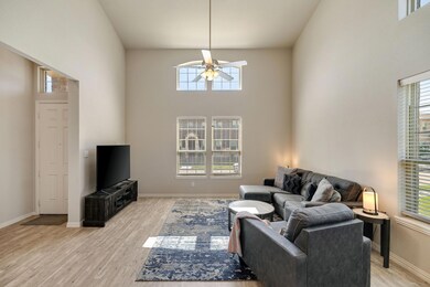 Living room featuring a wealth of natural light, a high ceiling, ceiling fan, and light wood-type flooring