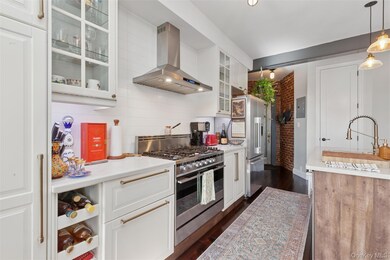 Kitchen featuring glass insert cabinets, white cabinetry, dark wood finished floors, ventilation hood, and appliances with stainless steel finishes