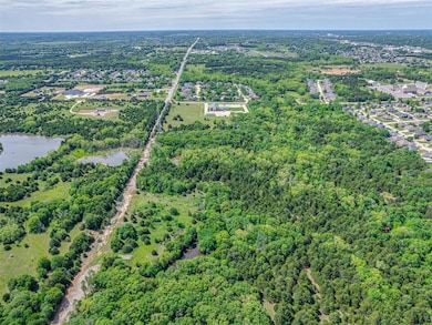 Aerial overview of property's location featuring a heavily wooded area and a nearby body of water