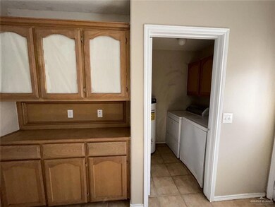 Clothes washing area with light tile patterned flooring, washing machine and clothes dryer, and cabinets