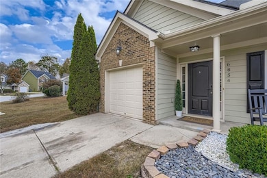 Entrance to property with brick siding, concrete driveway, covered porch, and an attached garage