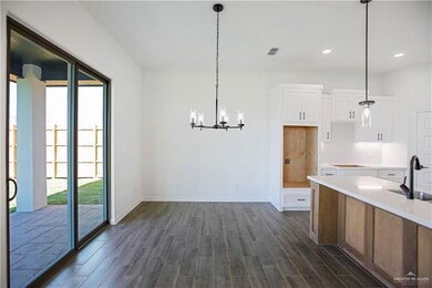 Kitchen with a sink, pendant lighting, white cabinetry, dark wood finished floors, and an inviting chandelier