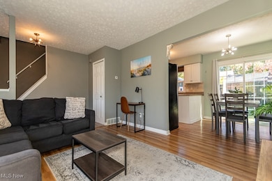 Living area featuring a chandelier, light wood-style floors, a textured ceiling, and stairs