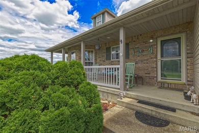 View of exterior entry with covered porch and brick siding