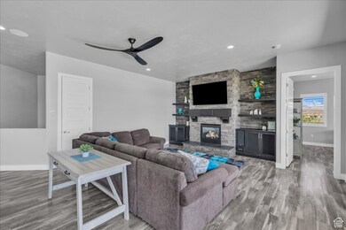 Living room with light wood-style floors, a fireplace, recessed lighting, and ceiling fan